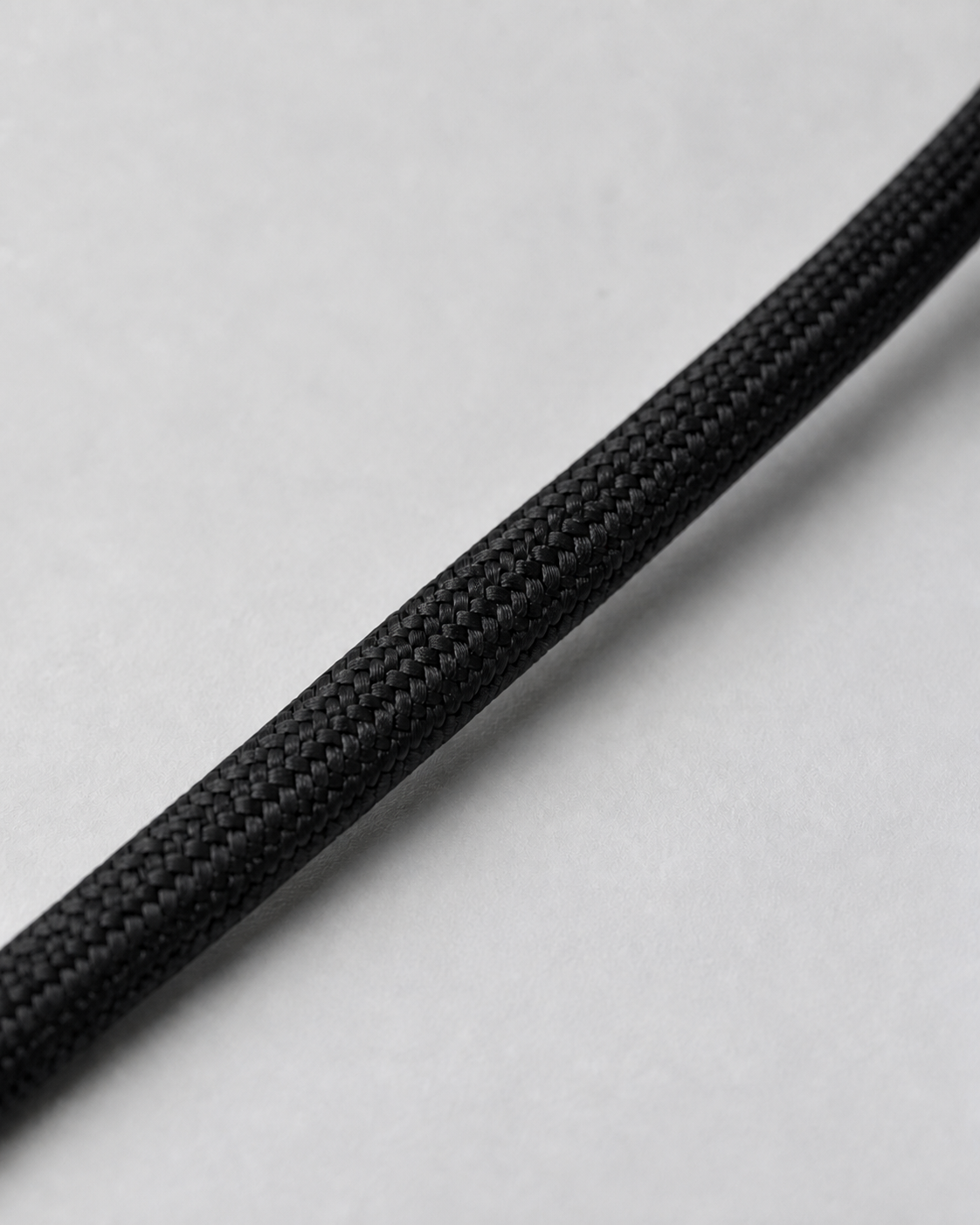 A macro close-up showing the braided texture of a single black paracord strand